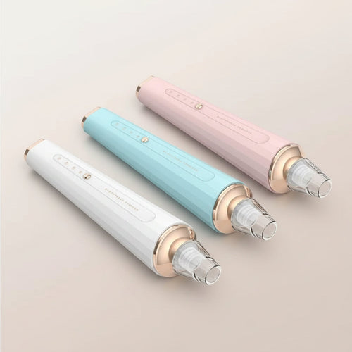Three handheld beauty devices in white, light blue, and light pink, arranged side by side on a soft beige background. Each device has a clear faceted top, a metallic gold collar, a vertical embossed logo, and a small round button near the bottom.
